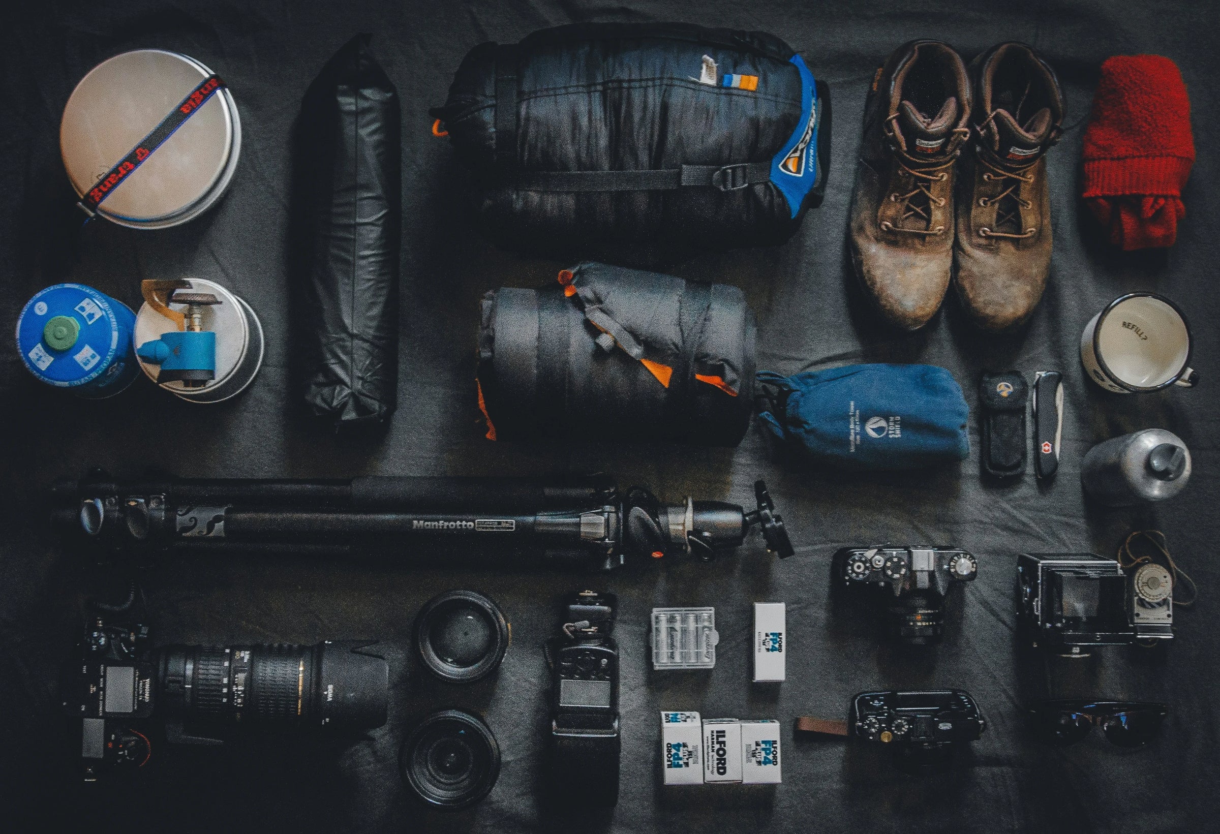 Collection of outdoor and travel gear on a dark surface